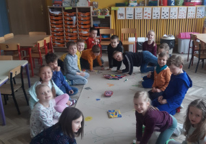 Dzieci siedzą na dywanie i malują